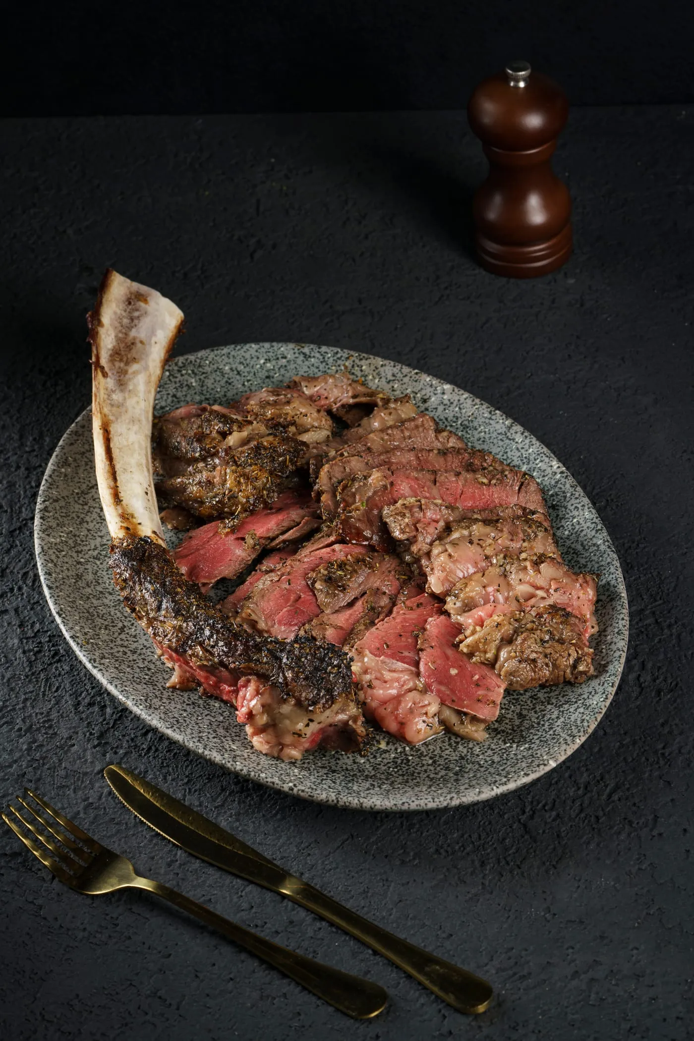 Sliced grilled steak on the bone, served on a ceramic plate