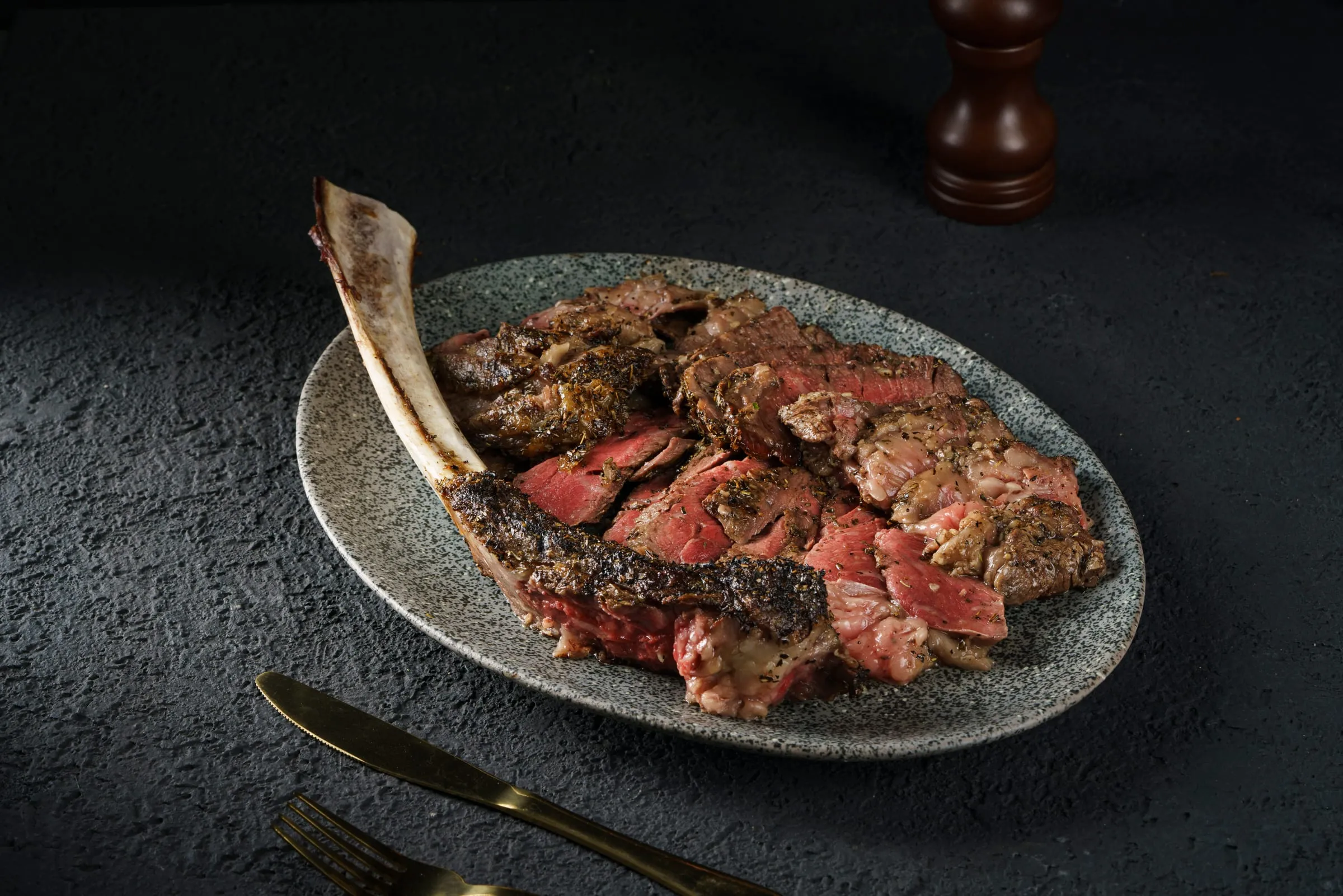Grilled tomahawk steak, sliced and served with salt and pepper